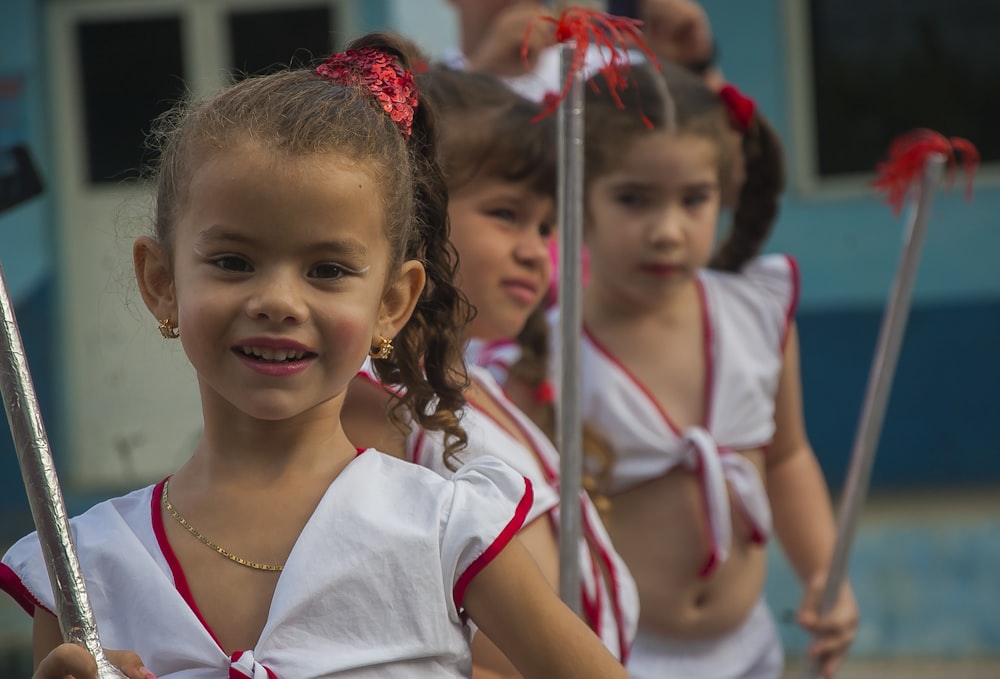 selective focus photography of girls in uniform holding sticks