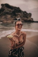 woman smiling and holding green fruit standing on shore during day