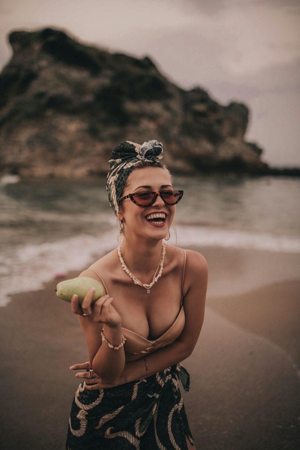 woman smiling and holding green fruit standing on shore during day