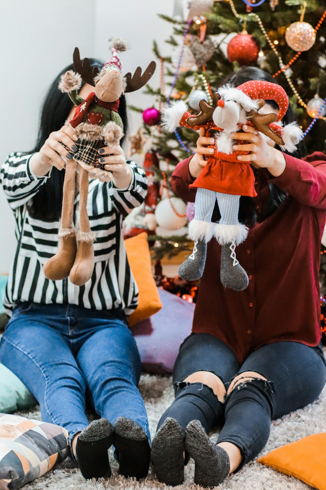 two women sitting on carpet while holding plush toys