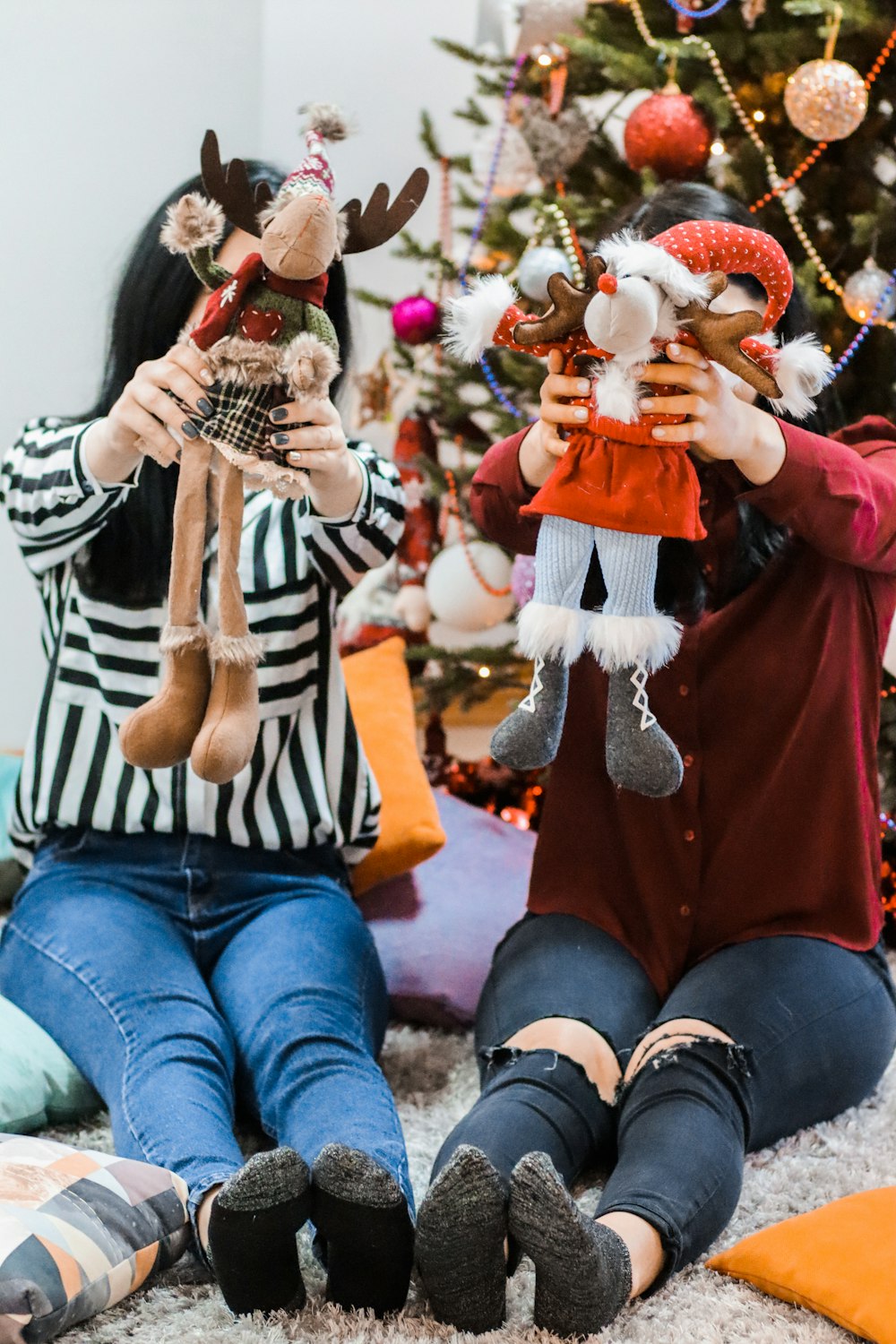 two women sitting on carpet while holding plush toys