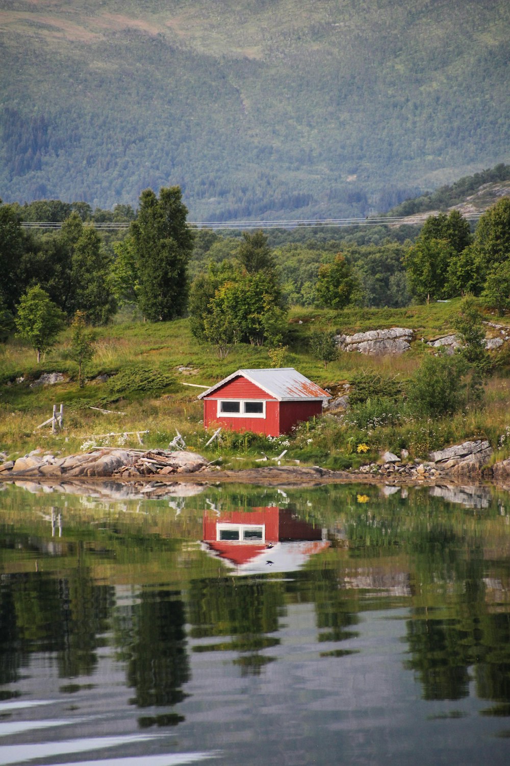 reflection of red and white cabin house on body of water