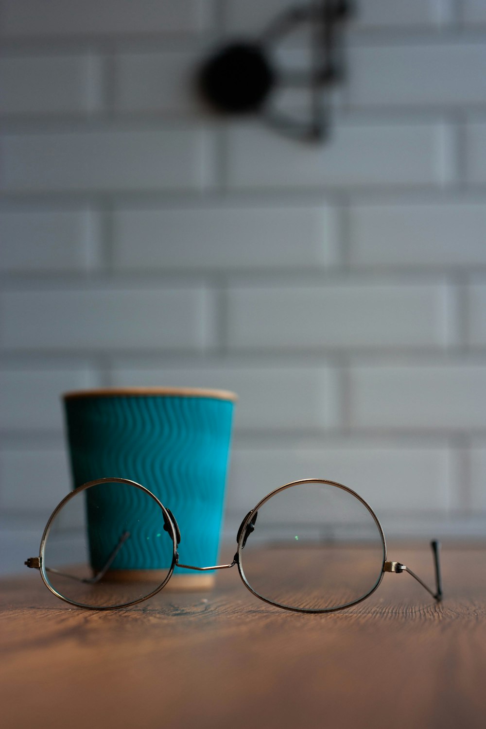 silver framed eyeglasses near blue disposable cup