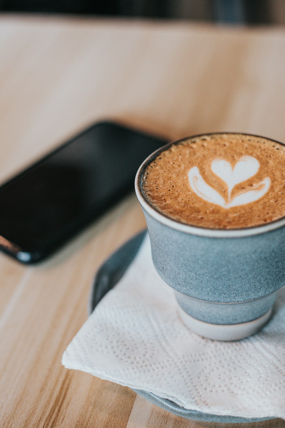 macro photography of cappuccino in mug on a table napkin