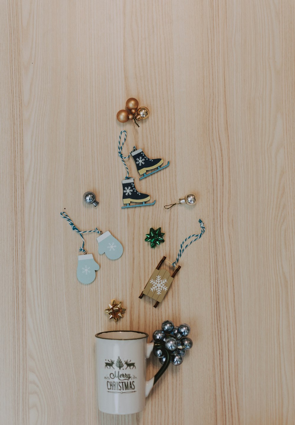 white and black printed mug near silver bauble, blue mittens, ice skates, and gold bauble hanging decors