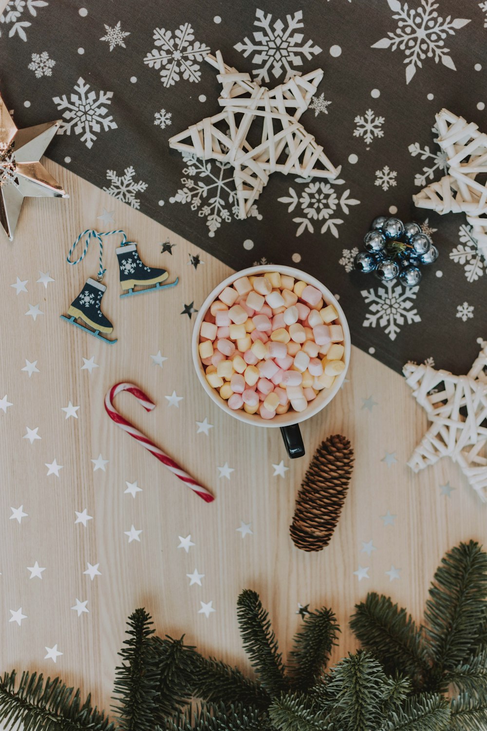 candy cane near marshmallow in bowl beside pinecone and Christmas decorations