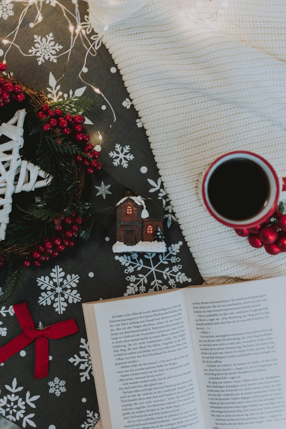open white book beside ceramic mug and Christmas wreath