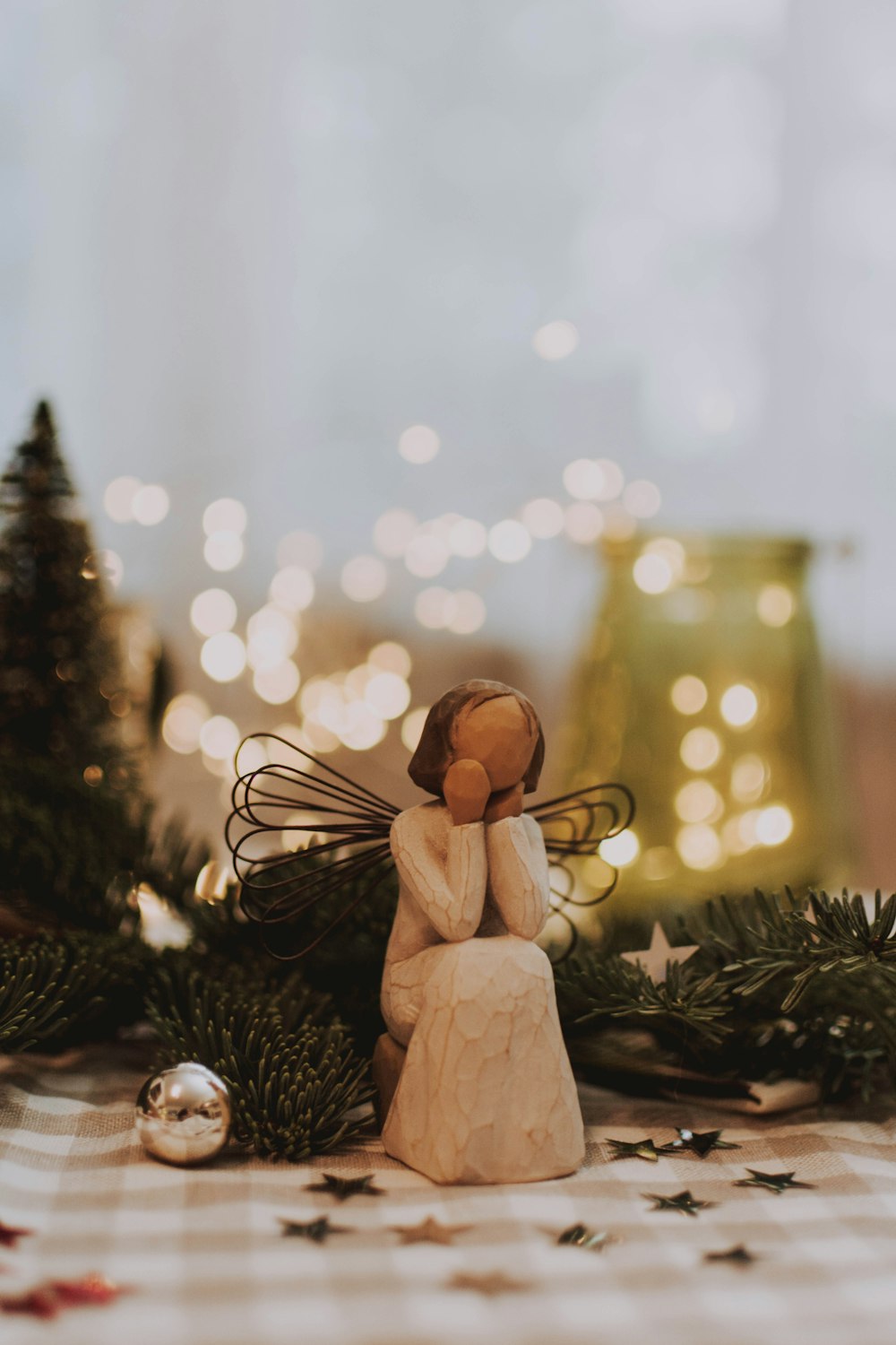 female angel sitting Willow Tree figurine near pine trees