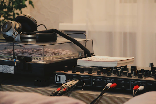 Close-up of headphones resting on a sleek black and silver turntable, with soft light reflections