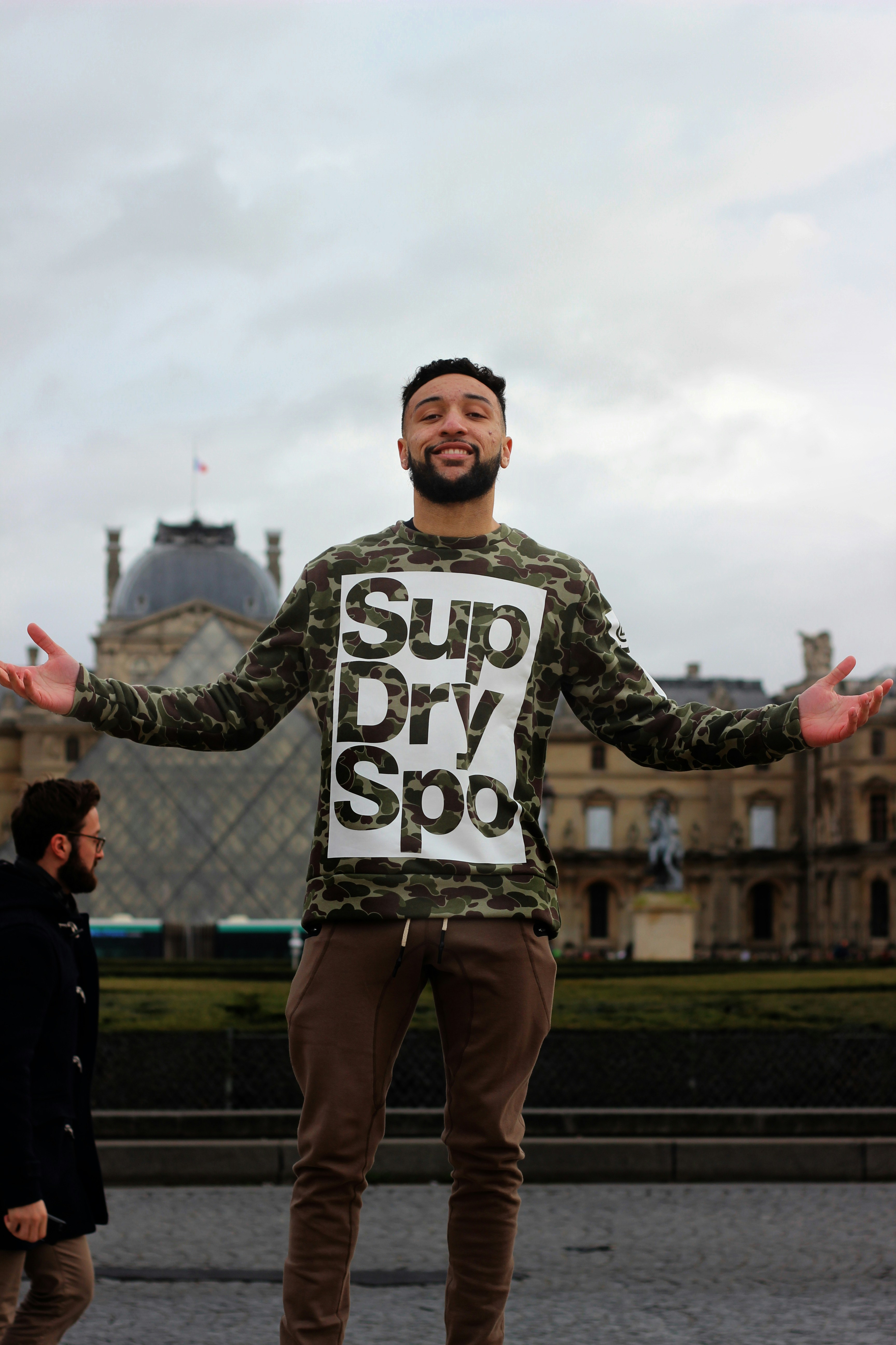 Homme portant une chemise à manches longues noire et grise et un pantalon de ville brun debout près du parc pendant la journée