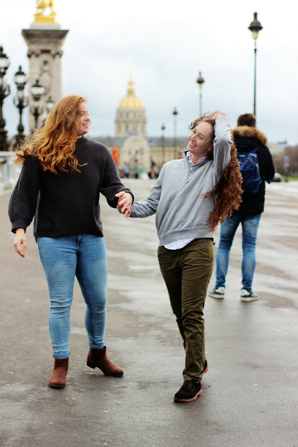 two women holding hands together while walking on road during daytime