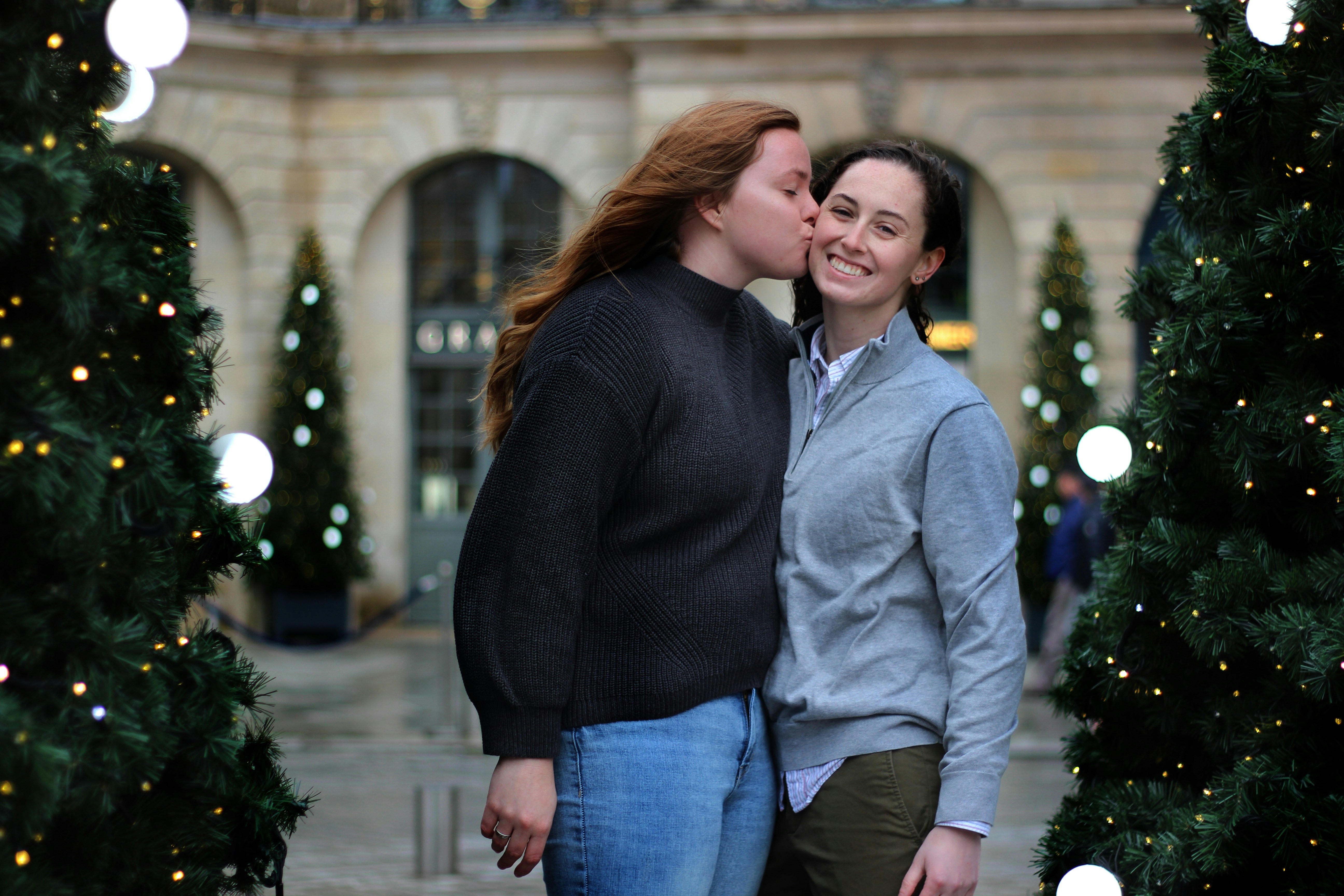 woman standing while kissing cheek of another woman