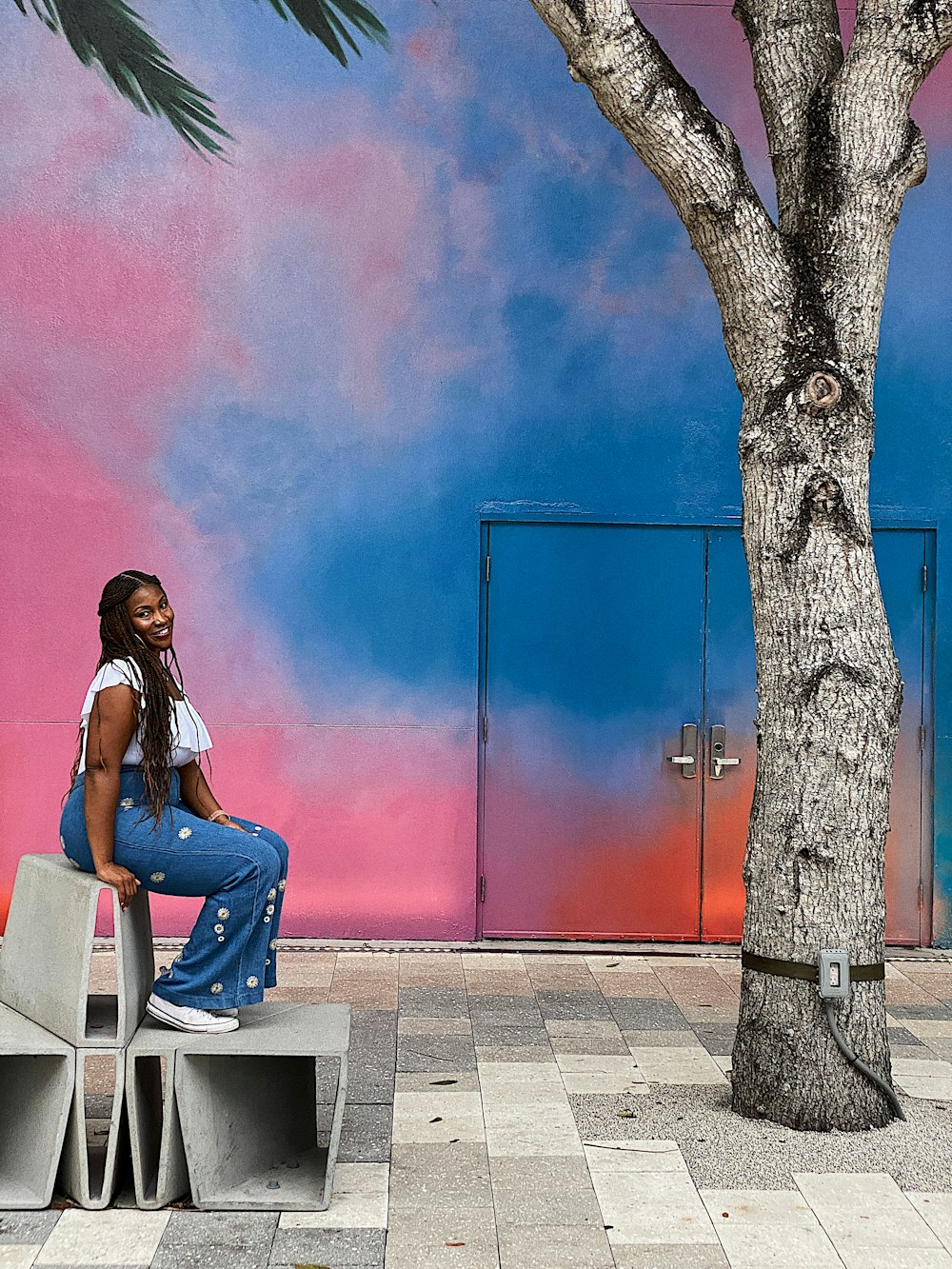 woman sitting on bench near tree and building