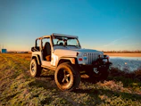 A bright yellow side-by-side with big tires parked on a muddy rock trail under a clear blue sky.