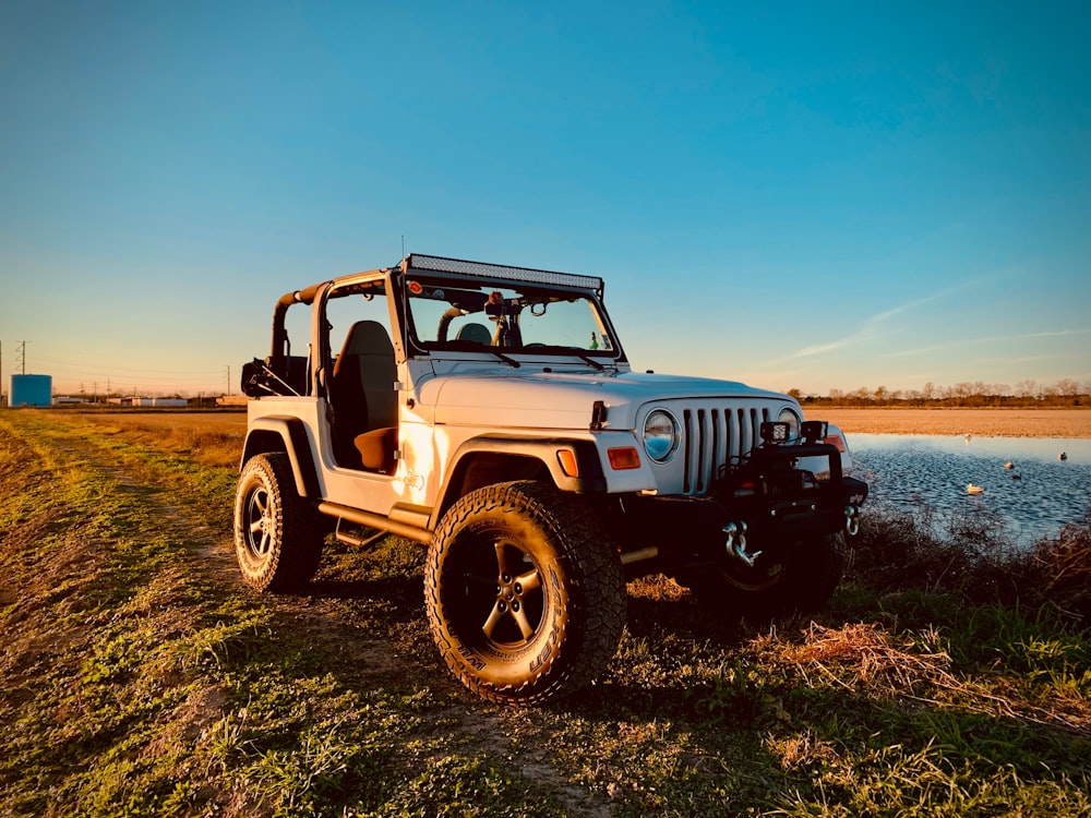 parked white Jeep Wrangler SUV beside body of water during day