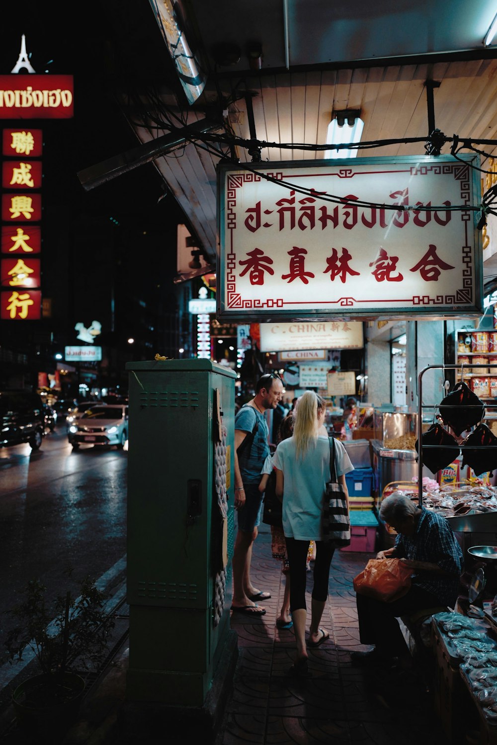 people walking on pathway near street and different vehicles on road during night time