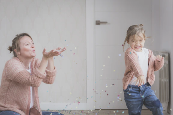 woman and child wearing beige sweater playing with confetti