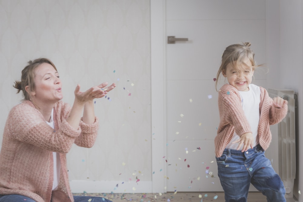 Mujer y niño con suéter beige jugando con confeti