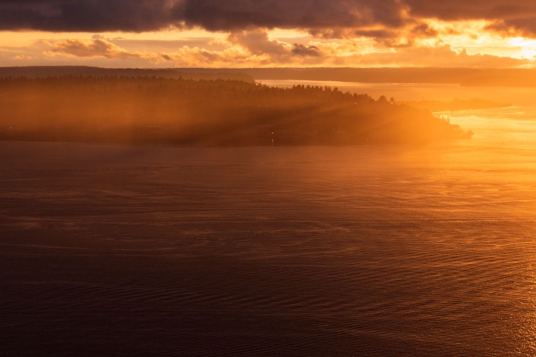 aerial photography of body of water viewing island under orange sky