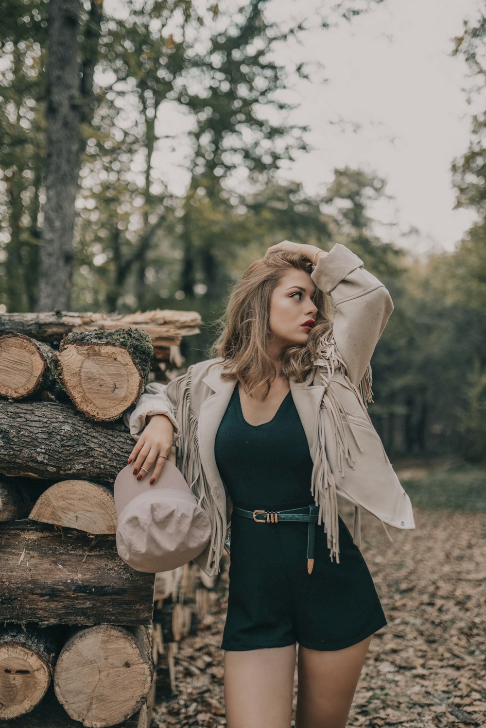 woman standing beside pile of logs during day