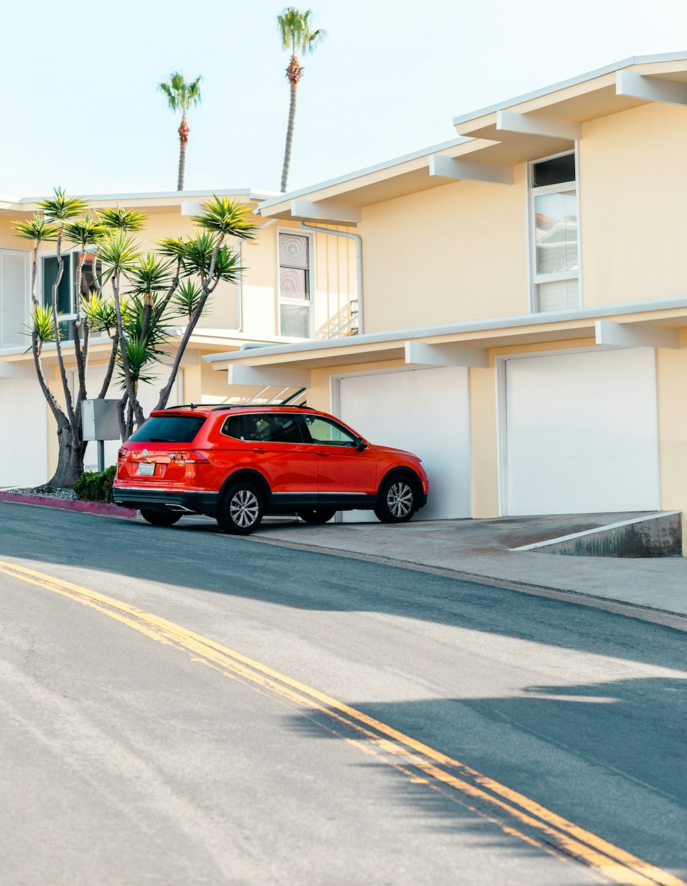 red SUV parking near beige 2-storey house