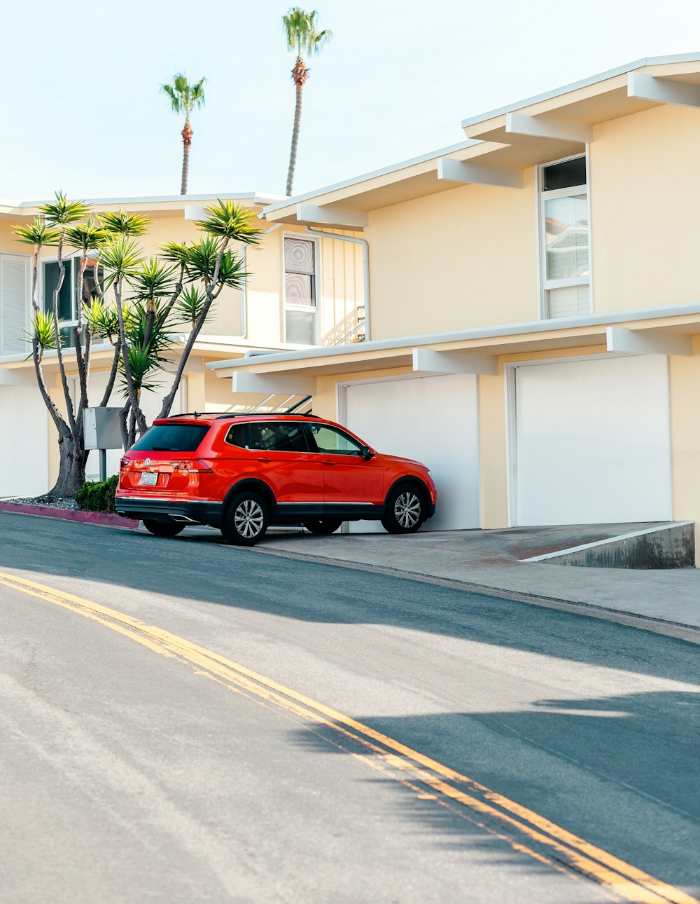 estacionamento SUV vermelho perto de casa bege de 2 andares