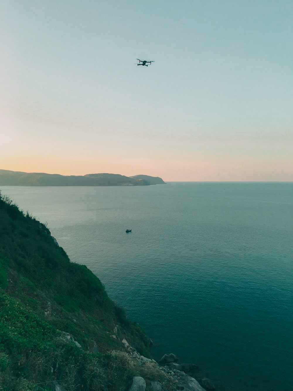 aerial photography of boat on body of water viewing mountain under blue and white sky