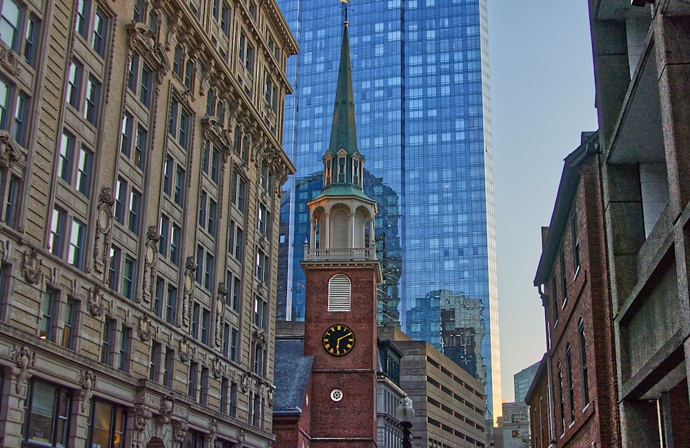 tower clock surrounded with high-rise buildings during daytime