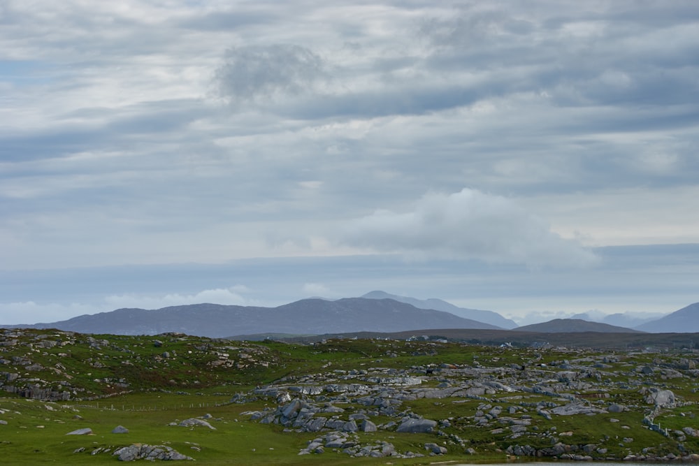 aerial photography of gray rocks on green field under blue and white sky