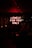 A dimly lit room featuring a neon red sign that reads 'LONELY FOR YOU ONLY.' The ambiance is dark, with subtle lighting highlighting the silhouettes of people sitting at tables, creating an intimate and mysterious atmosphere.