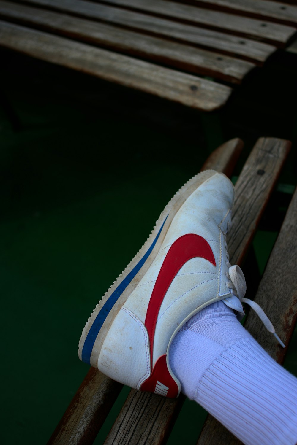 persona vestida de blanco y rojo con zapatilla Nike azul