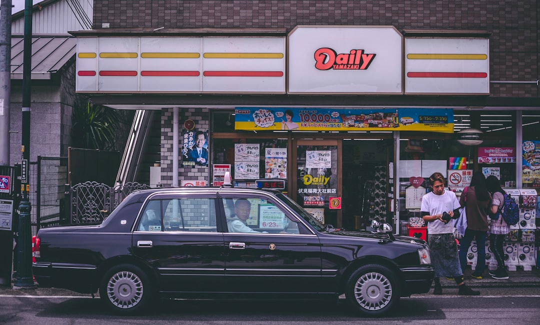 black sedan in front of Daily building