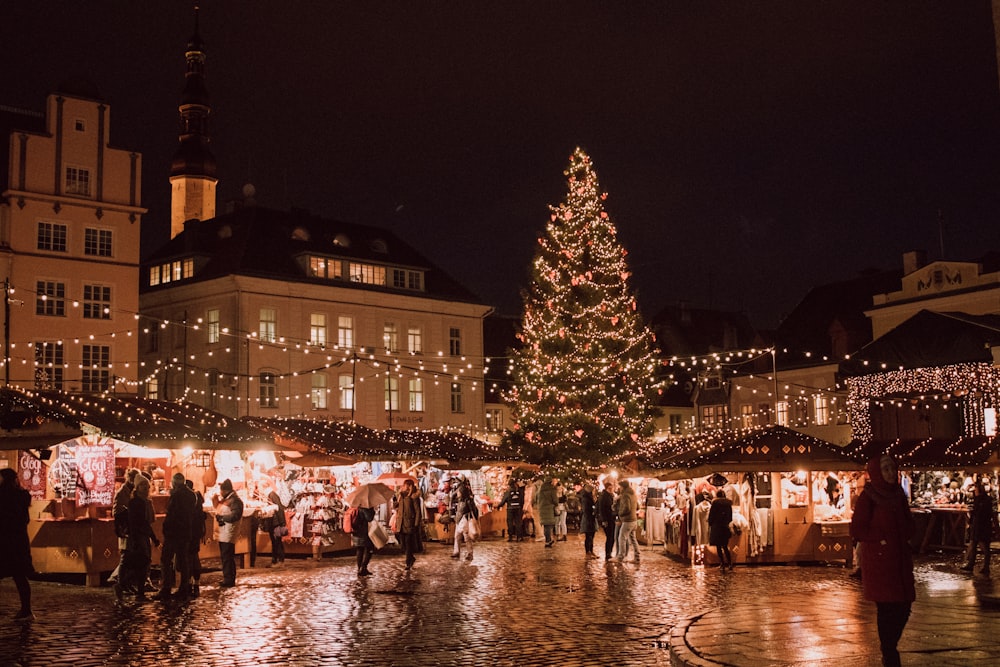 crowd walking in front of building near Christmas tree