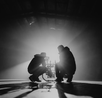 grayscale photography of two crouching men