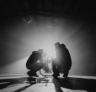 grayscale photography of two crouching men