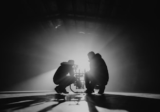 grayscale photography of two crouching men