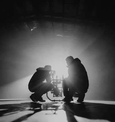 grayscale photography of two crouching men