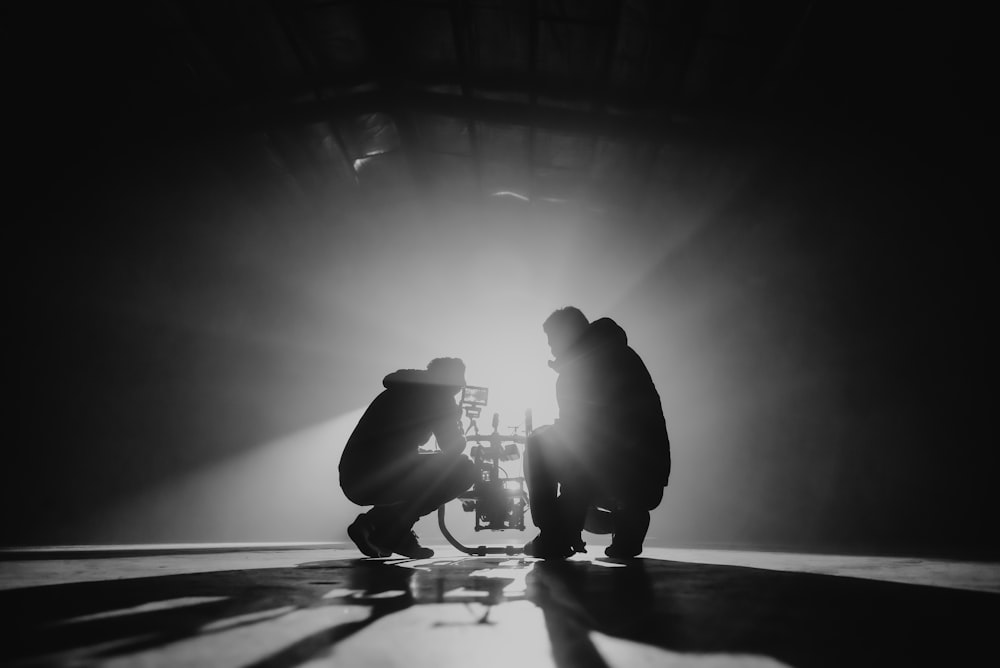 grayscale photography of two crouching men