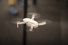 selective focus photography of flying white drone copter