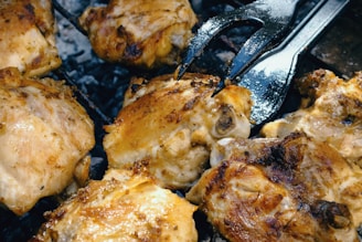 a close up of chicken on a grill with a fork