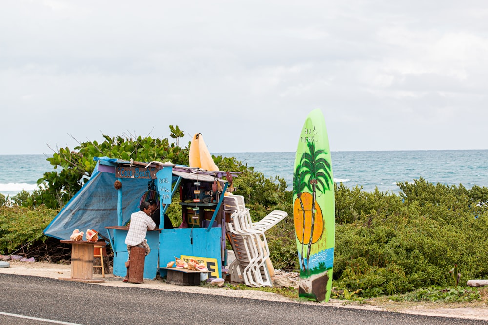 man standing in front of blue stall with surfboards