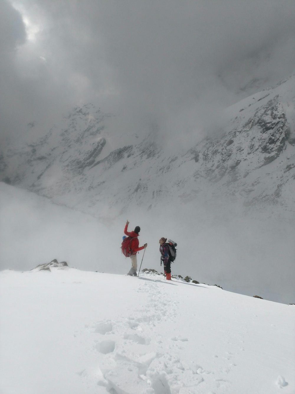 two people standing on snow-capped mountain