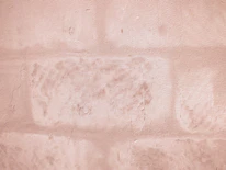 Close-up of a painter applying a smooth beige coat on an interior wall.