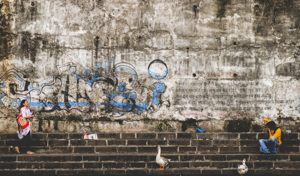 person talking photo of standing woman beside wall