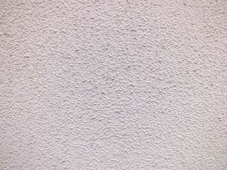 Close-up of a smooth, hand-applied stucco wall with subtle texture and warm earthy tones.
