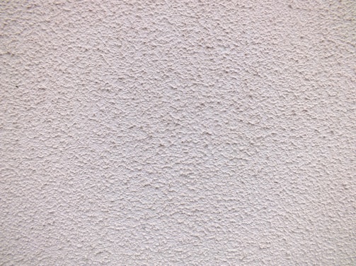 Close-up of stucco wall with fresh, smooth finish in natural light.