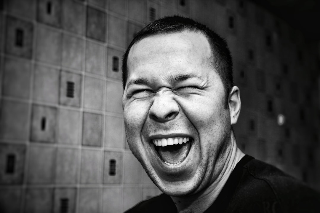 Grayscale photo of man laughing out loud.