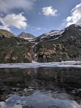 A serene Himalayan landscape with snow-capped peaks and a pristine water source at dawn.