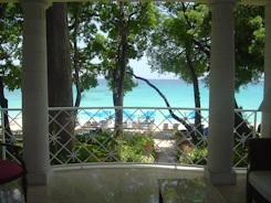 Sunlit beachfront condo balcony overlooking turquoise ocean waves