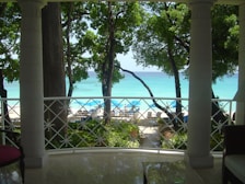 Balcony view of the beach with lounge chairs and gentle waves in the background.